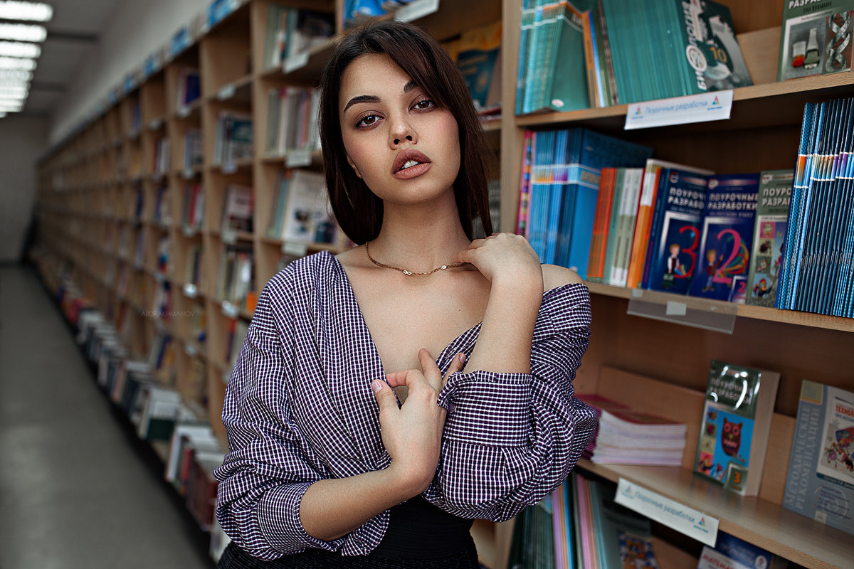 Красивая девушка в полосатой рубашке в библиотеке на фоне книг - Lenar Abdrakhmanov