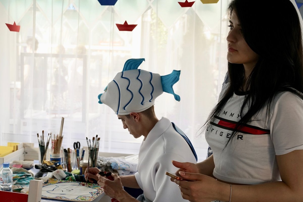 Юноша в шапке в форме рыбки рисует кошечку - Svetlana Shalatonova