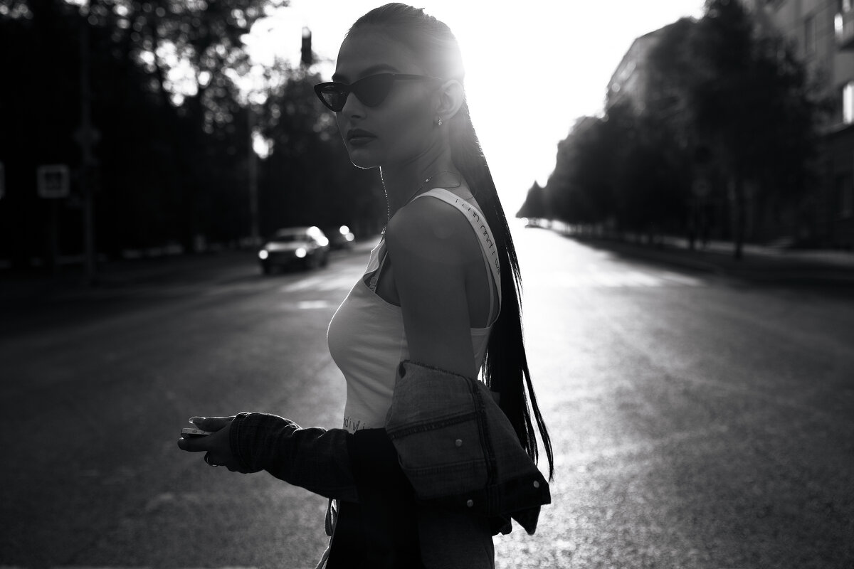 Красивая девушка в очках, белом топе и джинсовке гуляет по улицам солнечного города - Lenar Abdrakhmanov