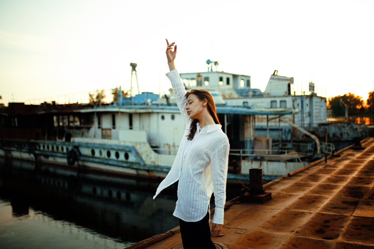Девушка в белой рубашке стоит на пирсе на фоне кораблей во время заката - Lenar Abdrakhmanov