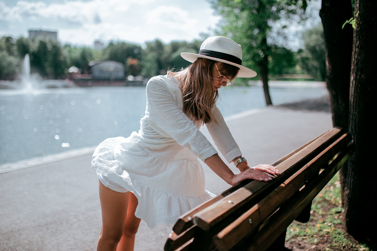 Девушка в белом платье и белой шляпе отдыхает у скамейки в парке - Lenar Abdrakhmanov