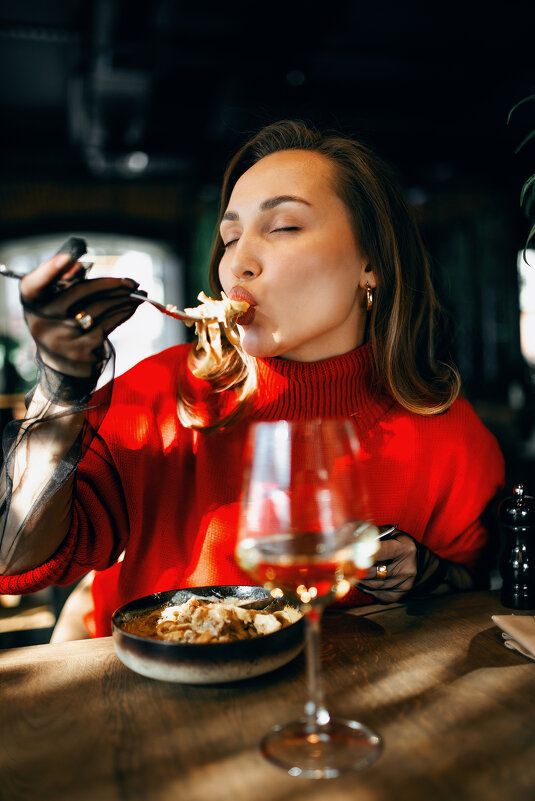 Девушка в красивом красном свитере в дорогом ресторане пьет вино и кушает пасту - Lenar Abdrakhmanov