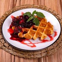 Сладкое вафельное печенье, политое ягодным вареньем в белой тарелке на плетеном деревянном подносе :: Павел Сытилин