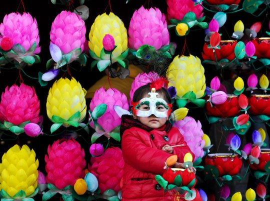 Девочка в маске для фестиваля около стены из лотосов