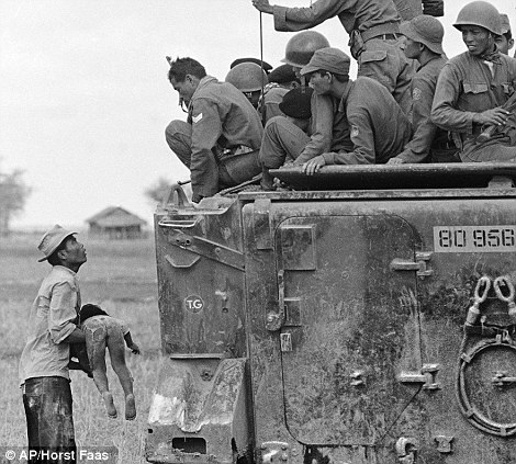 Отец держит тело своего ребенка перед солдатами Южно-вьетнамской армии