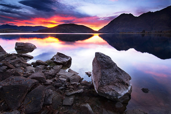 Озеро Ванака, Новая Зеландия. Для того чтобы получить эту фотографию, пришлось лечь на землю. Обратите внимание на то, как большой камень на переднем плане повторяет форму гор, отраженных в  воде.