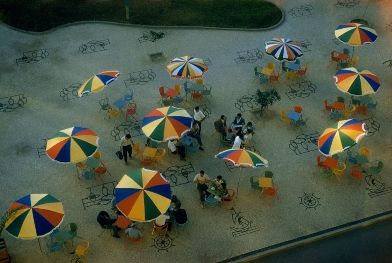 Радужные зонтики кафе украшают городской тротуар в Бенгеле, Ангола.