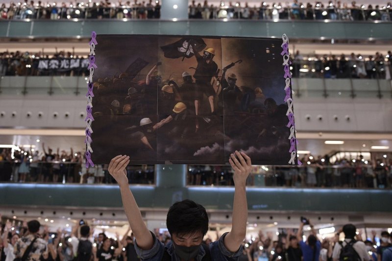 1 место в категории «Общие новости», 2020. Мужчина с плакатом среди людей, собравшихся спеть «Слава Гонконгу», негласный гимн демонстрантов в Гонконге, сентябрь 2019. Автор Николас Асфури.